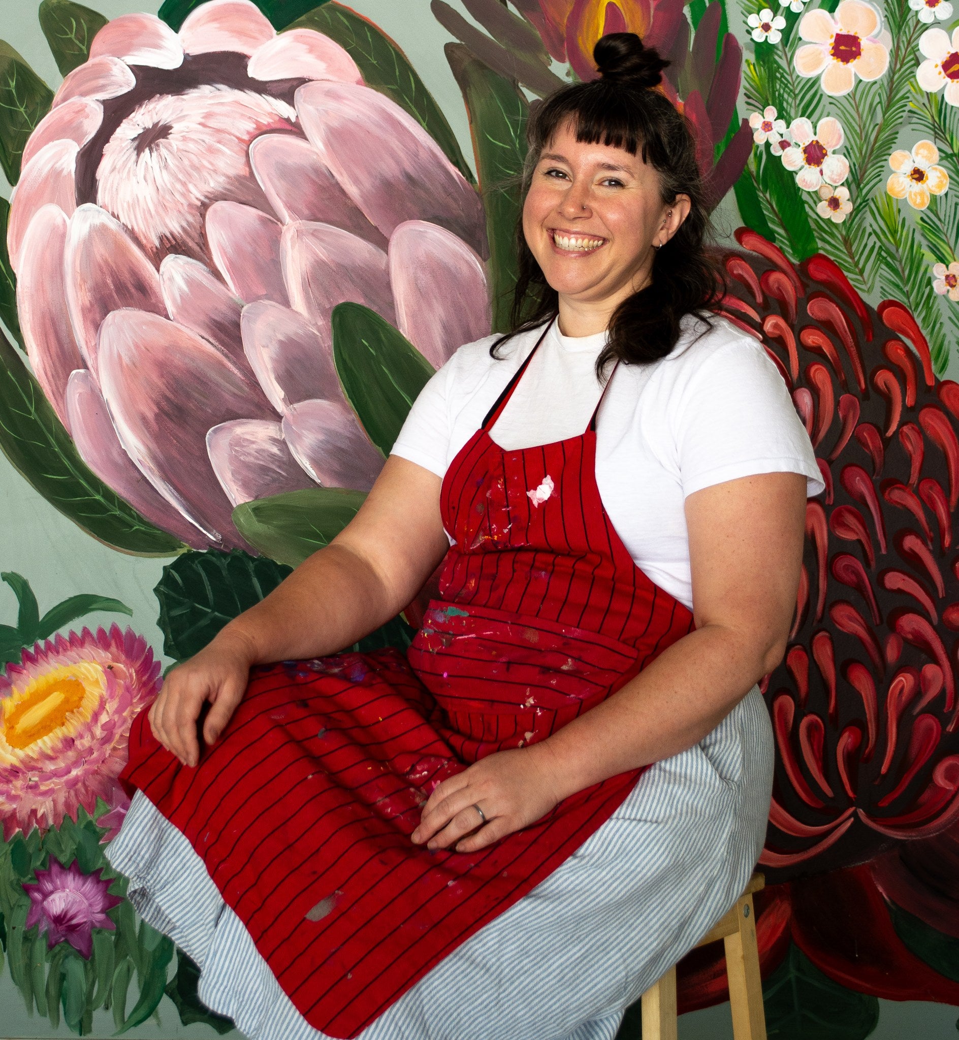 Kate Smith seated in front of one of her large native flora paintings