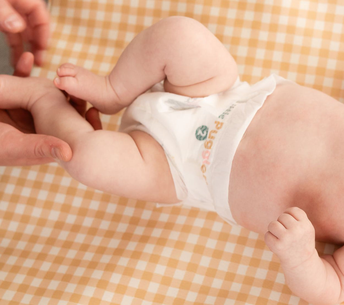 Close view of a baby's leg opening, with the leg elastic sitting down in the fold where the leg meets the hip rather than riding up on the thigh