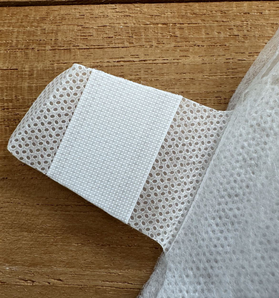 A nappy tab turned over, showing the field of tiny hooks that grip the front panel, with no adhesive strip