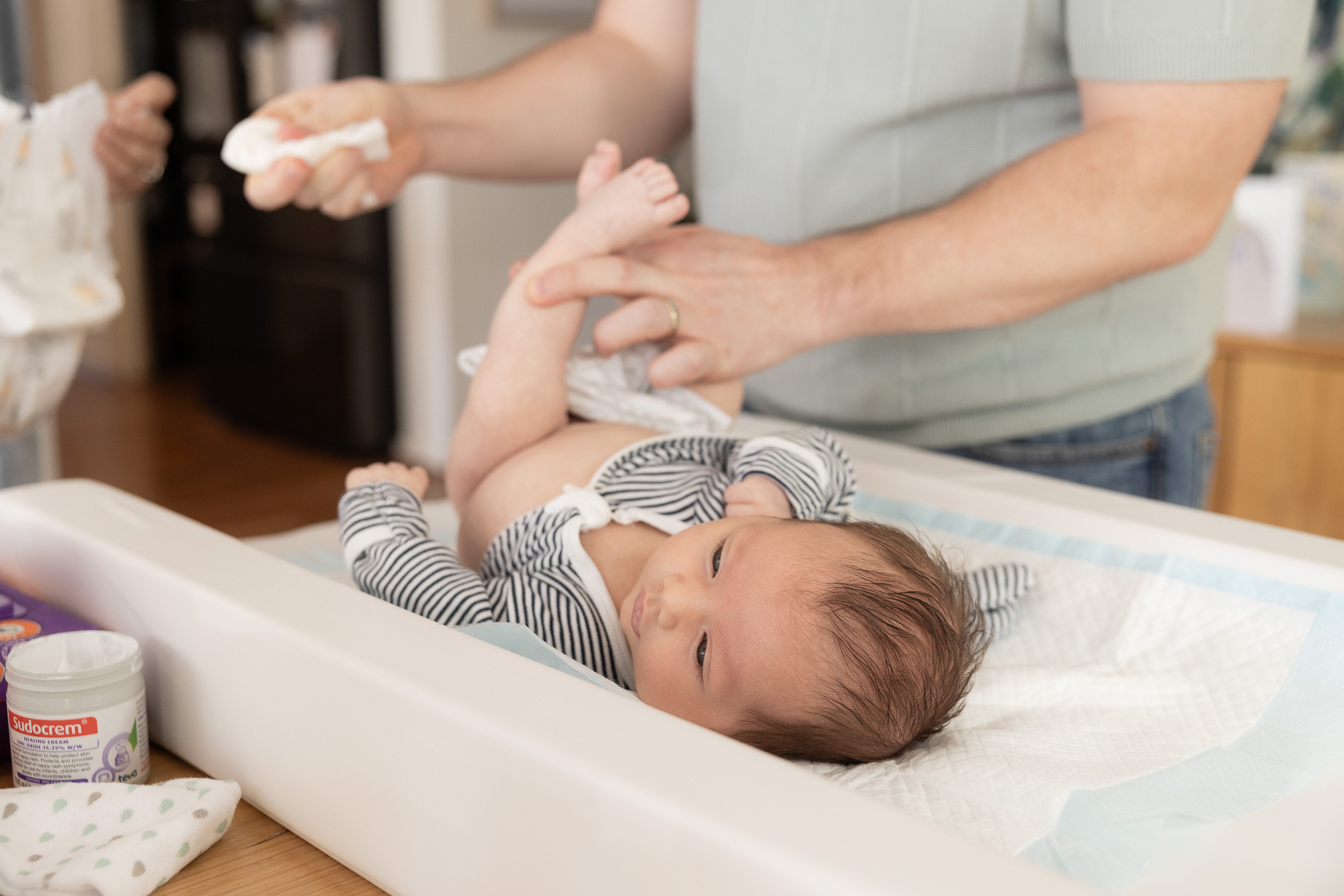 A father changing a newborn's nappy on a change table