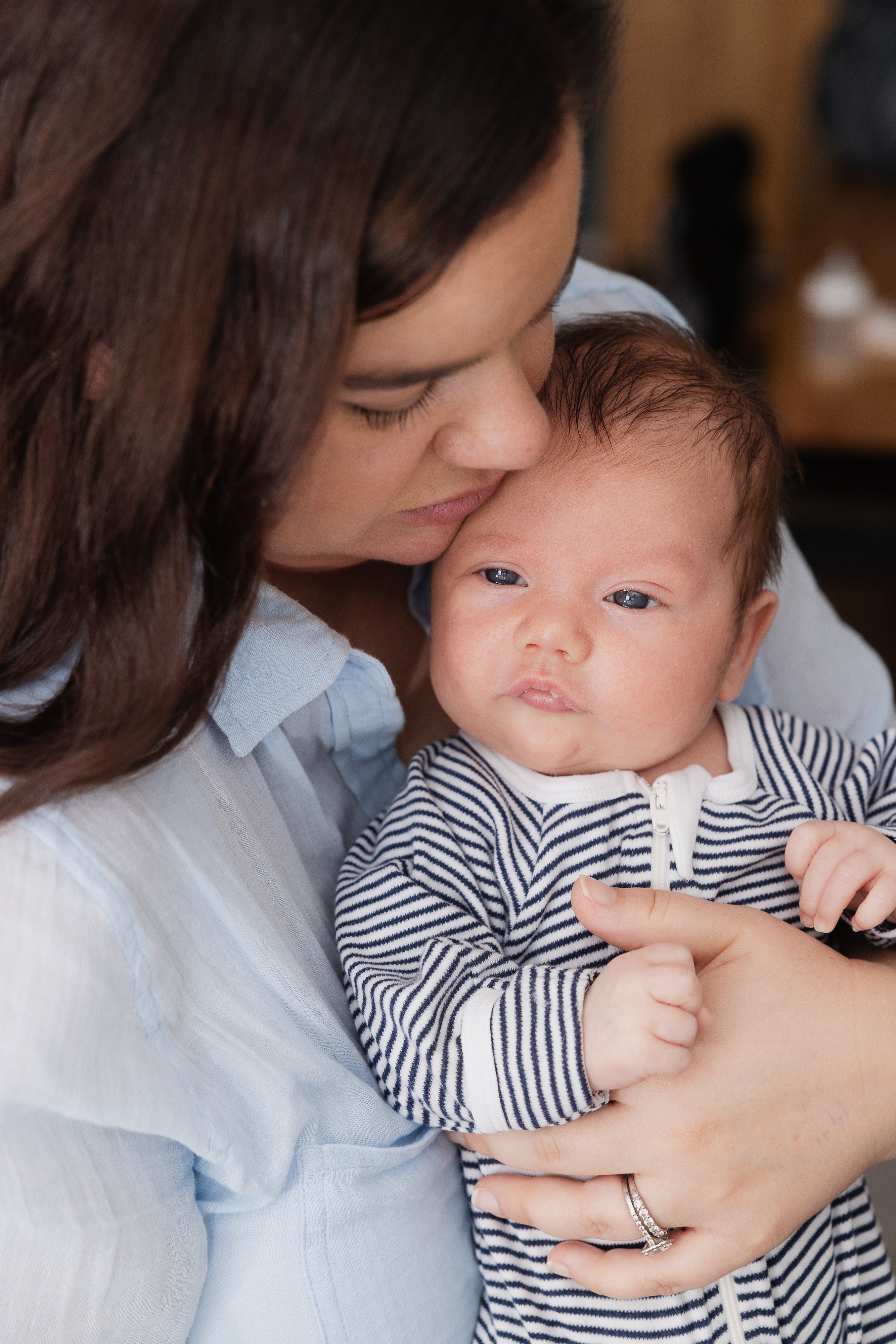 A mother holding her newborn close, her cheek against his