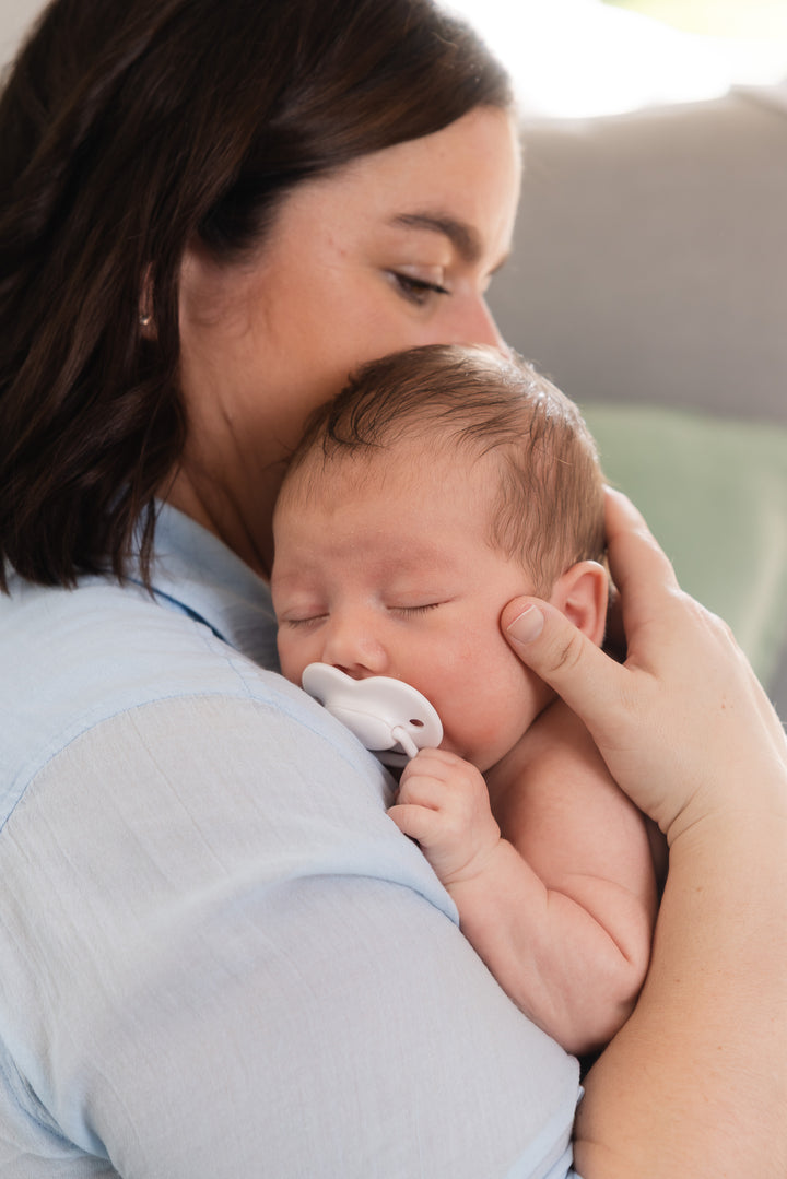 A newborn sleeping against their mother